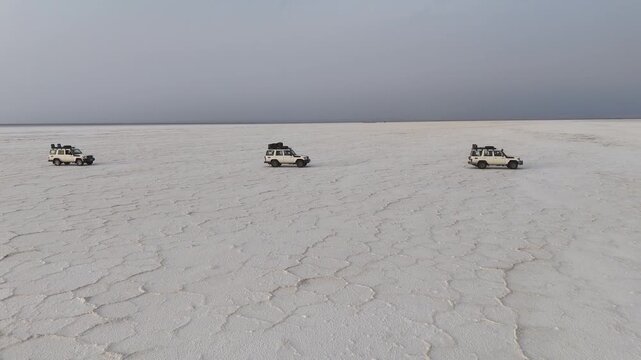 Aerial view of the salt flats in the Danakil Depression, in Ethiopia&rsquo;s Afar region. Vehicles driving on the flats. Tracking drone footage.