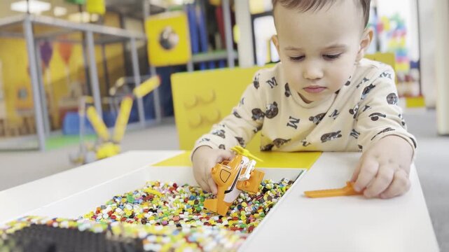 Toddler scooping colorful sensory beads