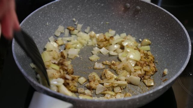 Chef Stirring Diced Onions and Spices in Frying Pan Close Up Saut&eacute;ing Ingredients