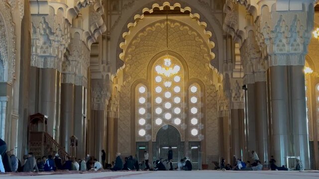 Majestic interior of Hassan II Mosque in Casablanca, Morocco. Features stunning Moorish architecture, intricate carvings, grand chandeliers, and peaceful prayer hall atmosphere. Perfect cultural asset