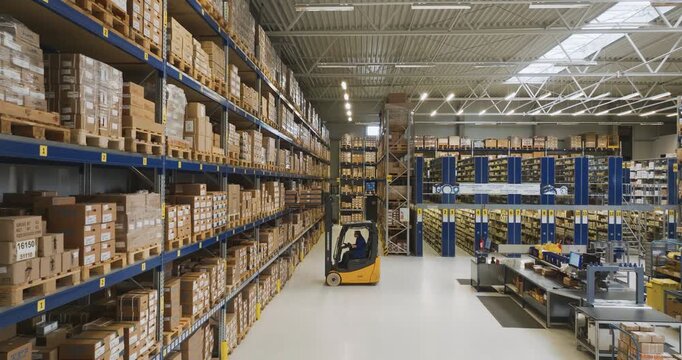 Industrial warehouse with forklift driver operating between high shelving units and storage racks