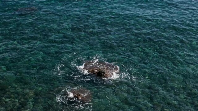 Stunning underwater view of crystal clear water and rocky shoreline in tropical paradise. Half underwater slow motion of turquoise water, rocks and trees on tropical island 