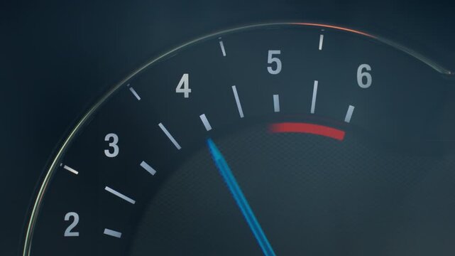 Close up of illuminated car tachometer on dashboard with blue needle showing engine RPM. Concept of driving, engine performance, vehicle control and automotive technology