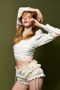 Elegant young woman showcasing fashion in a confident and artistic pose against a muted background