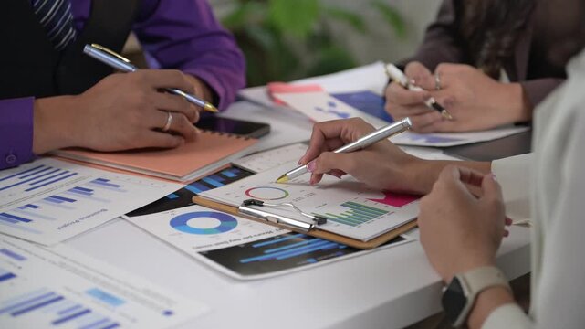 A group of people are working on a project, with one person writing on a clipboard. Scene is focused and collaborative, as the group works together to complete their task