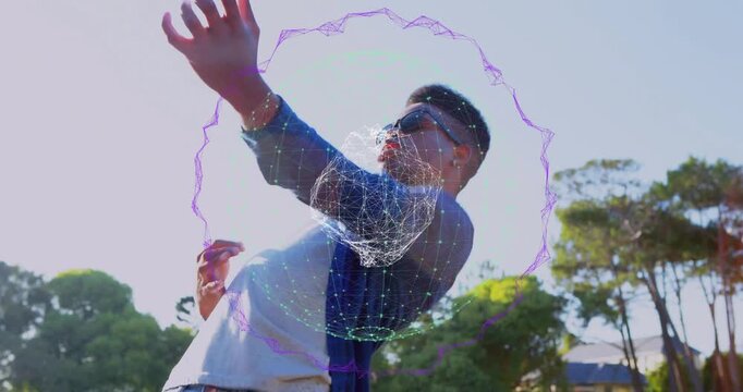 Man raising right arm in sunny park, activating orbiting shrinking orb showing tech via dance