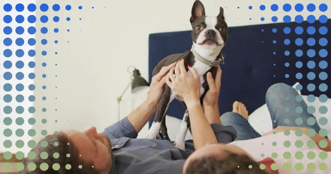Couple on bed lifting, steadying dog to adjust pet collar as orange overlays pulsing over them