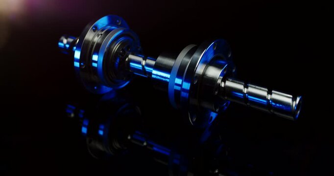Close up of a metallic ball screw spindle with blue illumination in a dark industrial setting