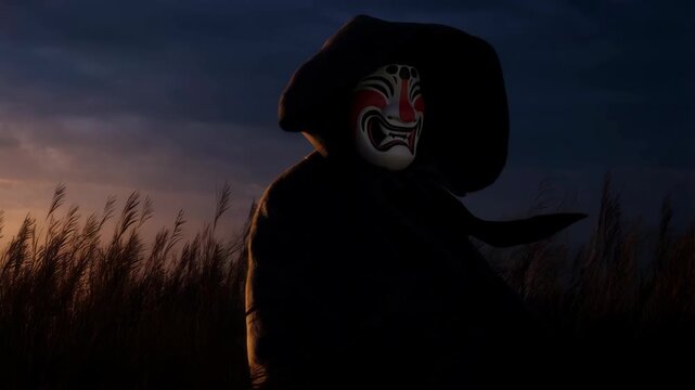 Person wearing a traditional Japanese Noh theater mask in a dark hooded cloak standing in a field at dusk with a dramatic sky