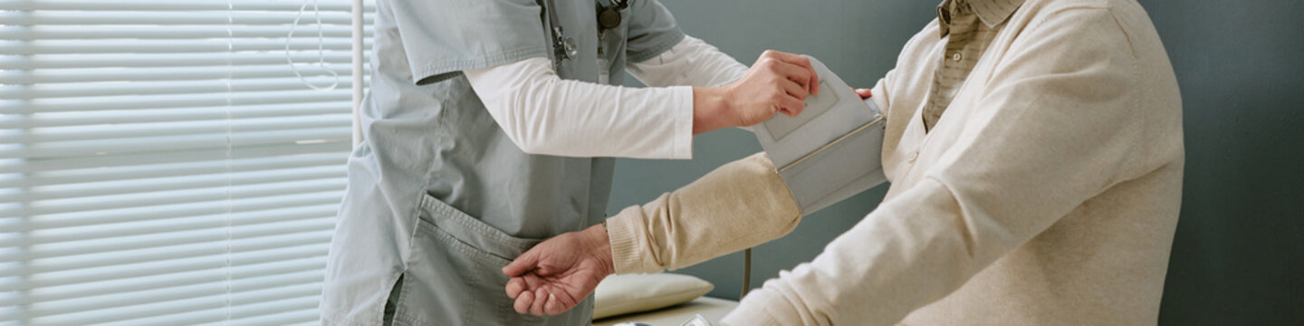 Close up of patient receiving blood pressure check from healthcare worker during medical exam, supporting preventive care messaging and clinic service promotion