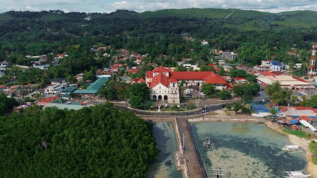 Wide aerial of Baclayon Church town and coastline with bridge and coastal water Bohol Philippines, drone