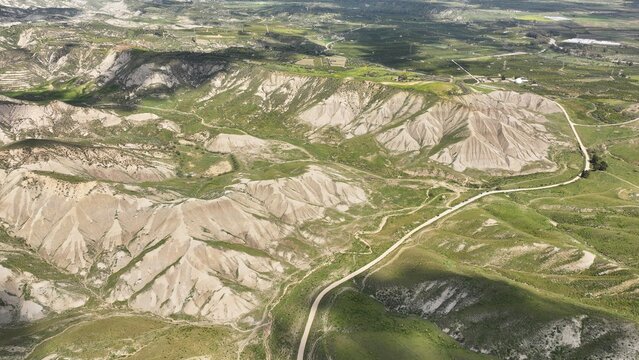 Aerial view of a stark landscape where the rugged earth rises in dramatic ridges, punctuated by patches of verdant life, Centuripe, Sicilia, Italy.