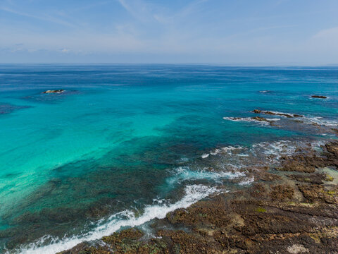 Aerial view of turquoise waters meet rugged, rocky shores under the vast blue sky, Erissel, Socotra, Yemen.