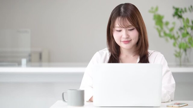 自宅でパソコンを使いながらタイピングする在宅勤務やリモート勤務や資格の勉強をする女性のデザイナーやフリーランスのビジネスイメージ動画