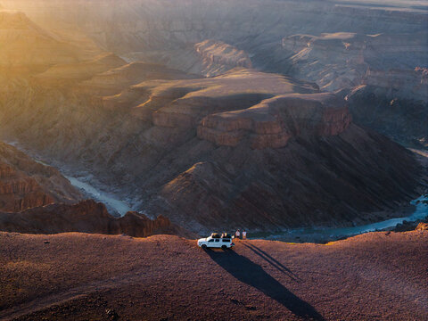 Aerial view of the stark, rugged Fish River Canyon reveals a dramatic landscape carved by time, with warm light painting the cliffs, Fish River Canyon, Karas Region, Namibia.