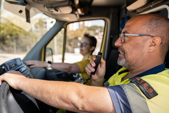 Paramedics driving ambulance while using walkie talkie