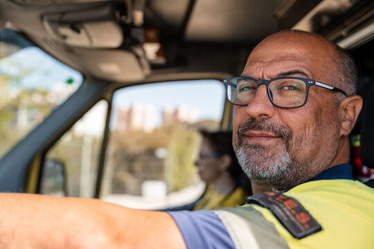 Paramedic driving ambulance with colleague in the background