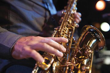 Obraz premium A captivating close-up of a saxophonist playing in a dimly lit venue showcases the beauty of the instrument's shine and the musician's intense focus on their craft.