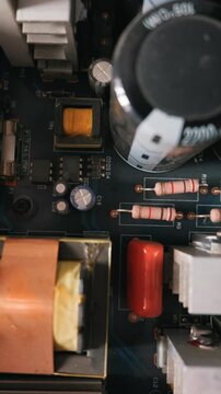 Printed circuit board features large electrolytic capacitors and colorful resistors in a vertical macro close-up. This represents a modern technology concept of electronics and hardware engineering