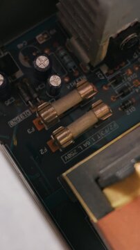 Detailed macro view of a printed circuit board showing glass fuses, electrolytic capacitors, and diodes mounted on the dark blue surface. The concept highlights modern electronic hardware.