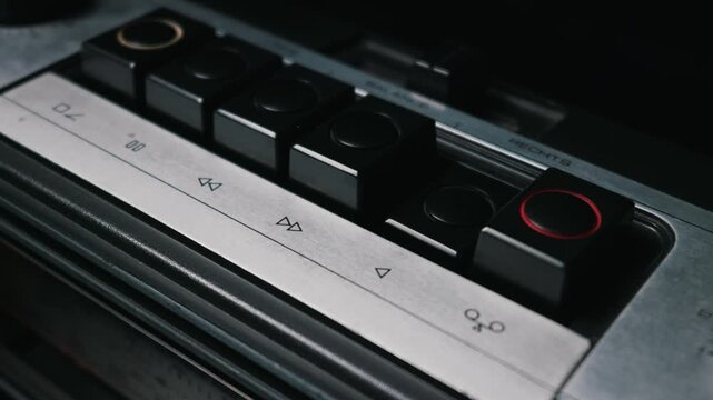 A male finger pushes the play button on a vintage silver and black audio tape recorder. This concept highlights retro technology, nostalgia, and analog media playback.
