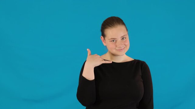 Girl playfully points finger at person making Call me hand gesture. Young woman gestures towards man with eyes sparkling with flirtation