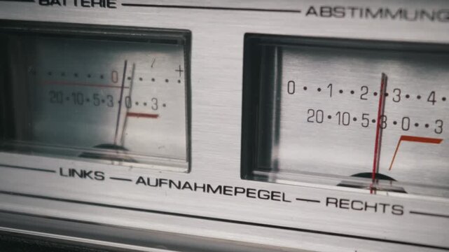 Vintage analog audio VU meters accurately measure recording levels with sharp macro focus emphasizing the delicate red needles. Concept of retro audio technology and nostalgic high fidelity sound