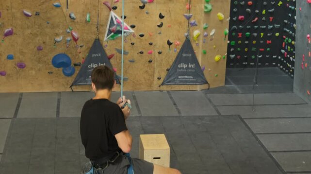 Climber rappels down on safety ropes after overcoming height. Man coped with difficult discipline at rock climbing training session