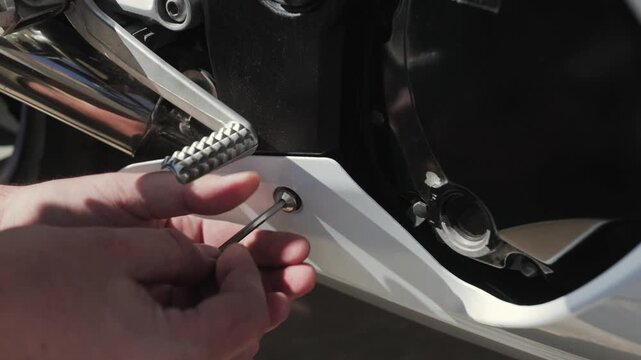 Closeup amateur mechanic unscrewing bolt from motorcycle fairing with socket wrench