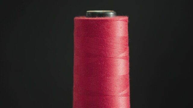 Close up of red sewing thread spool with soft light minimal textile background
