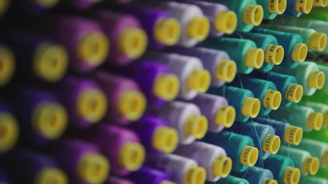 Colorful sewing thread spools arranged in rows textile industry pattern background