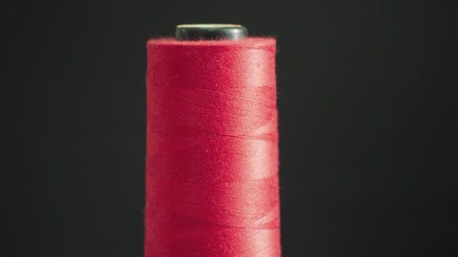 Close up of red sewing thread spool with soft light minimal textile background