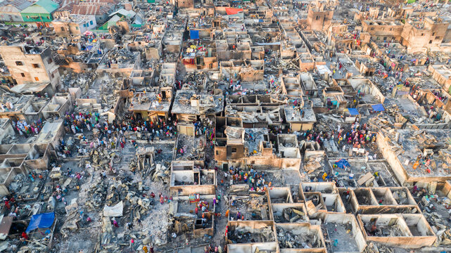 Aerial view of the aftermath of devastation with people amidst the rubble, a stark contrast of human presence against the grey ruins, Dhaka, Dhaka Division, Bangladesh.