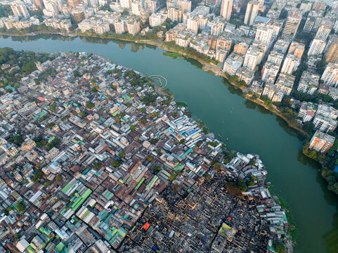 Aerial view of stark contrasts between dense settlements and modern high-rises along the winding river, a visual narrative of urban disparity, Dhaka, Dhaka Division, Bangladesh.