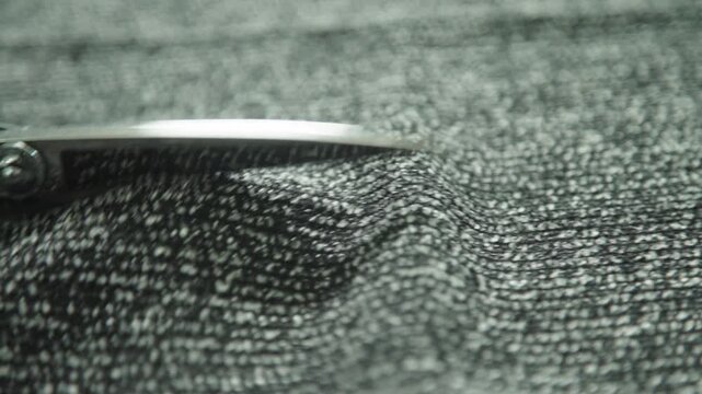 Close up scissors cutting textured fabric material tailoring textile production