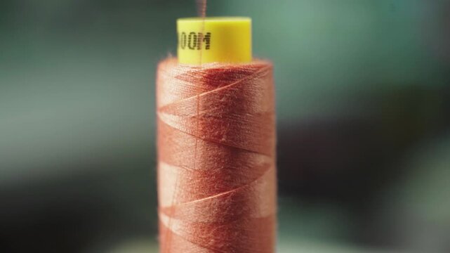 Red sewing thread spool close up textile material minimal background