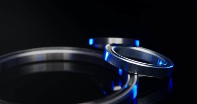 Close up of different industrial metallic ball bearings with blue light reflection on a black surface