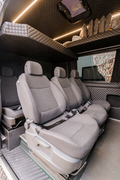 Interior of a customized passenger van with grey fabric seats and quilted black ceiling panels.