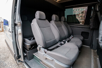 Naklejka premium Interior View of Empty Passenger Seats in a Modern Grey Utility Van with Quilted Upholstery and Natural Light