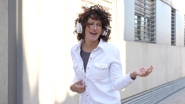 A young woman enjoys her favorite music outdoors, stylishly wearing trendy headphones