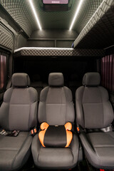 Naklejka premium Interior of a luxury passenger van with quilted grey upholstery and integrated sleeping platform.