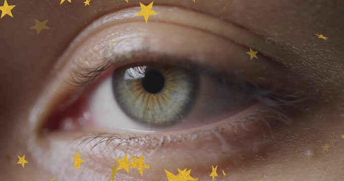 Female right eye lowering and blinking in beauty ad, revealing iris as gold star confetti drifting