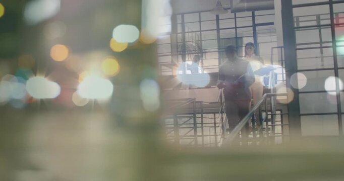 Descending man in dark shirt, woman in light blouse reading folders at office ramp, bokeh fading