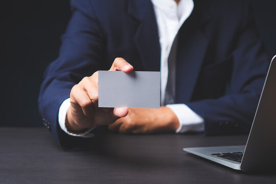 Businessman holding blank business card over laptop
