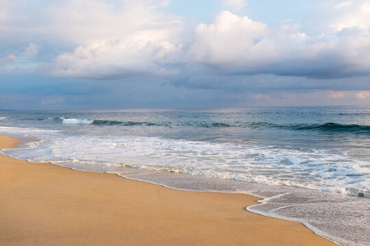 Clouds over ocean waves on empty beach