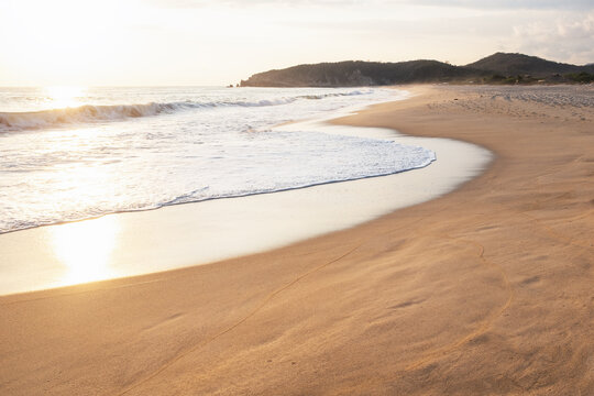 Sunlight reflecting in ocean waves on empty beach
