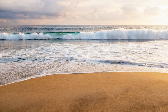 Clouds over ocean waves on empty beach