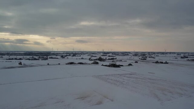 Wide drone shot of wind turbines and sun rays in winter.