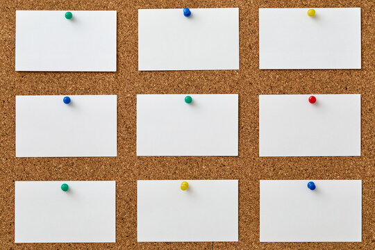Blank pieces of paper attached to cork board with colorful push pins