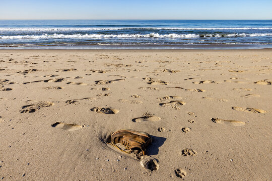 Abandoned boot and footprints on empty Santa Monica Beach
